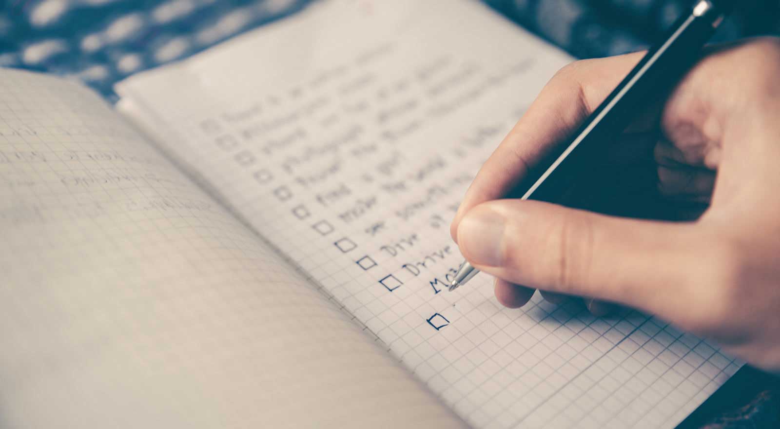Jemand schreibt eine Liste in ein Notizbuch